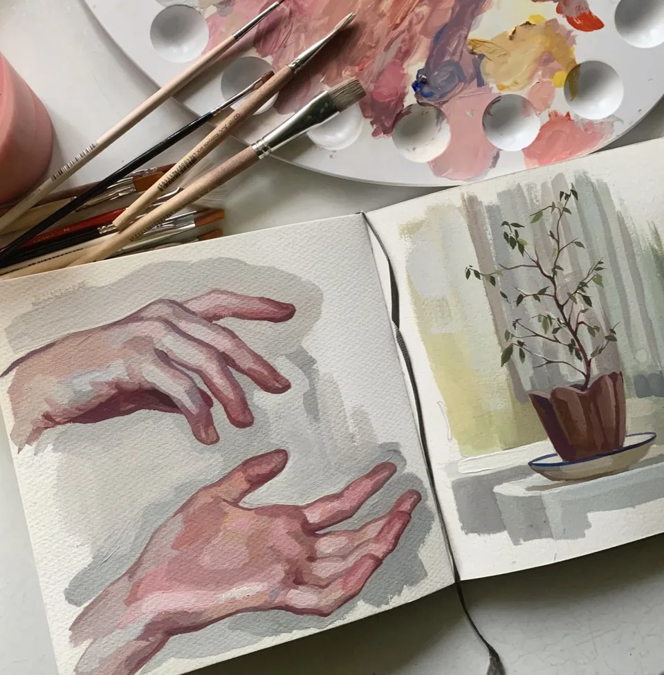 Open sketchbook with gouache studies of hands and a green plant